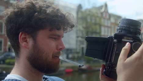 man using classic analog camera in amsterdam - close up