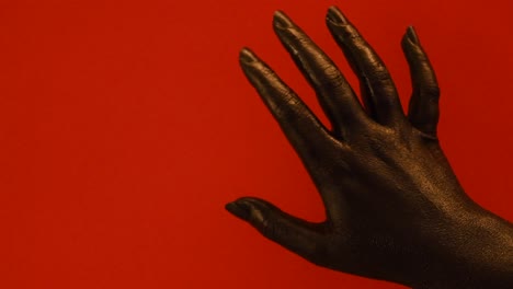 young female hand painted with black color moving smoothly in a red background