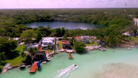 drone shot of homes and jet skier at bacalar mexico with a small pond or lagoon in the background