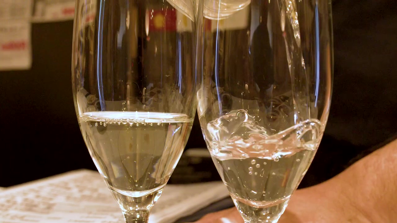 Un cameriere versa vino di riso trasparente in due bicchieri in un ristorante a Kanazawa, Giappone.