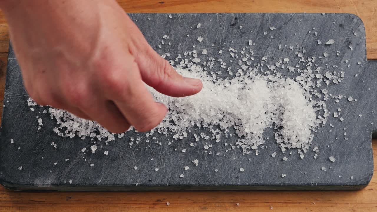 Hand sprinkling salt on a cutting board