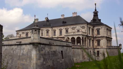 Old-castle-made-from-gray-stones.-Birds-fly-in-cloudy-sky-above-antique-palace