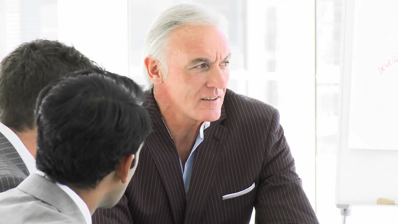 고위 관리자가 회의에서 그의 팀과 이야기하고 있습니다.