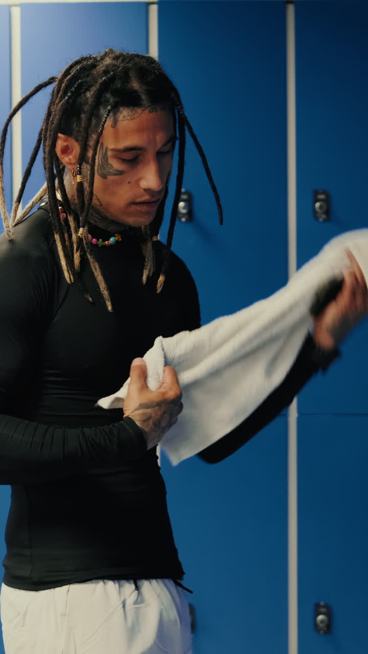 Mand med dreadlocks forbereder sig i et omklædningsrum i fitnesscenter