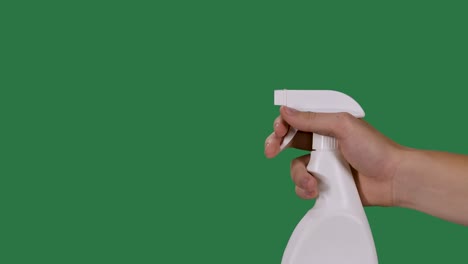 male hand holds a spray bottle and sprays a disinfectant alcohol agent to disinfect the covid 2019 corona virus. green screen, chroma key. slow motion. close up