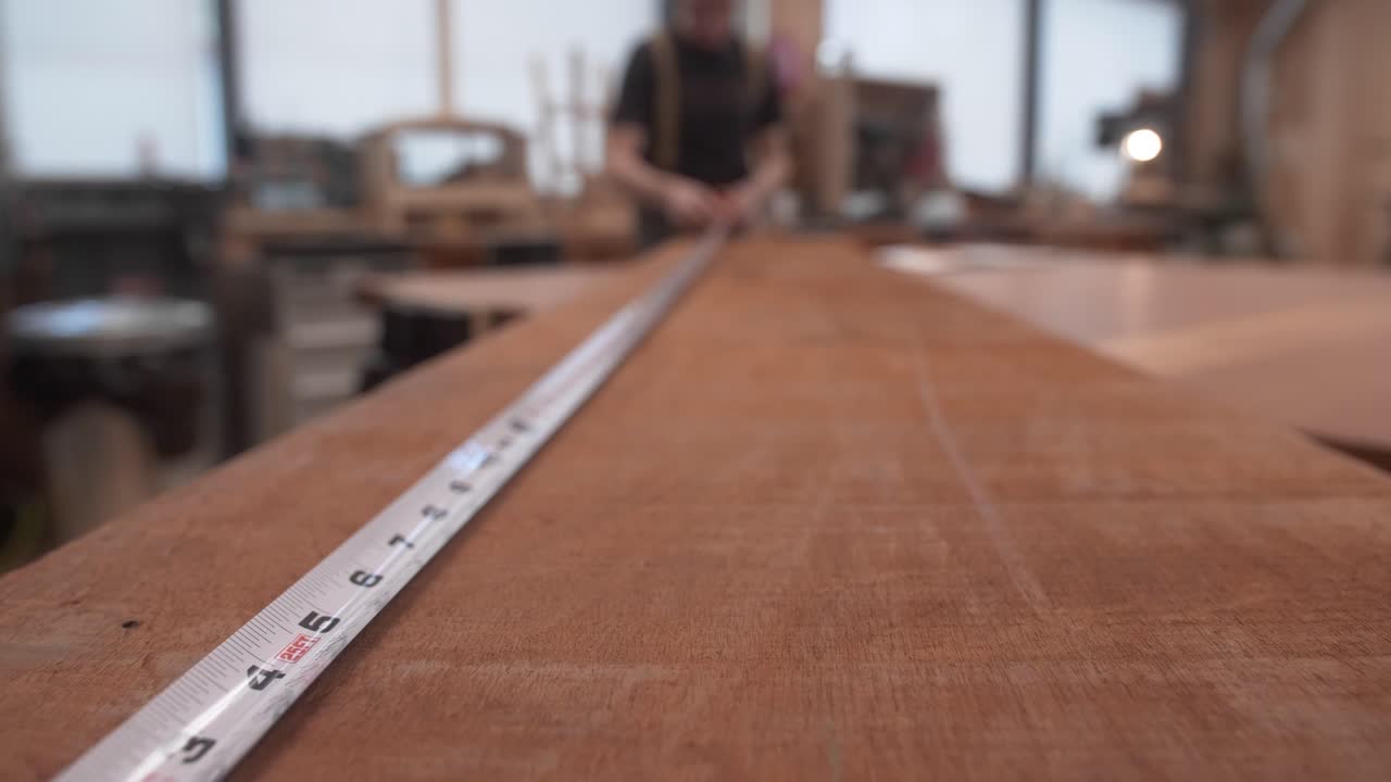 carpintero midiendo las dimensiones de la madera en el banco de trabajo con cinta métrica
