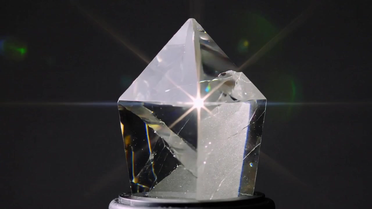 Projecteur lumineux intense révélant des fractures internes dans un cristal facetté, posé sur un piédestal noir en studio