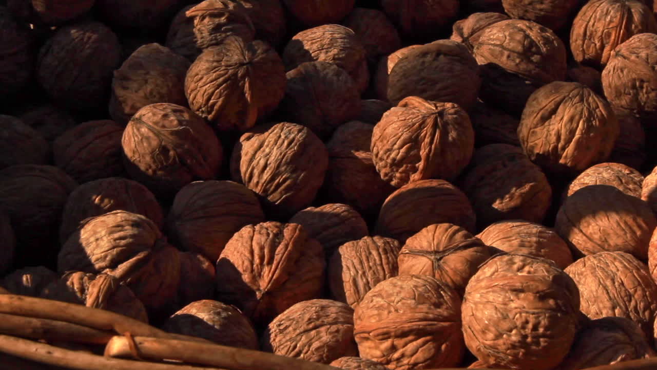 Close up walnuts inside wicker basket. pan right