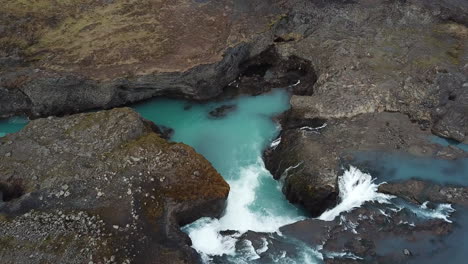 Filmische-Luftaufnahme-Des-Himmlischen-Türkisfarbenen-Gletscherwasserfalls-Und-Der-Tiefen-Vulkanischen-Schluchtklippen-Im-Hochland-Von-Island