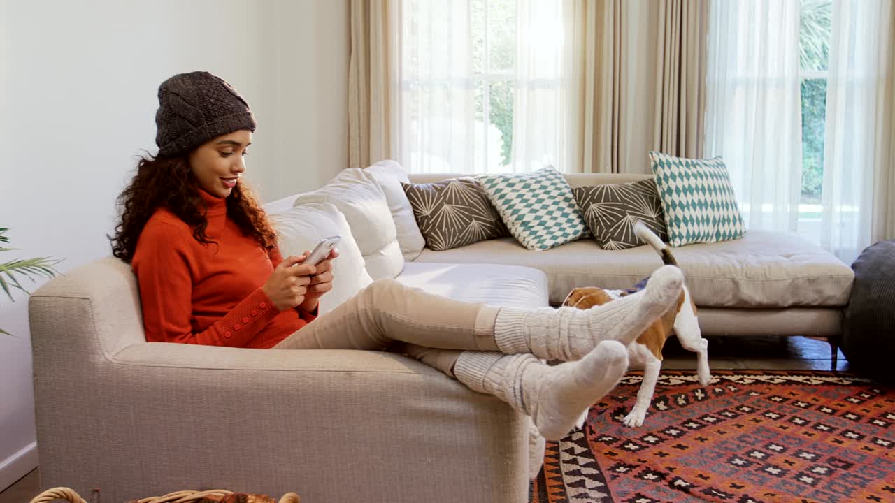 개 가 소파 에 앉아 있는 여자 에게 가까이 와서 휴대 전화 4k 4k 를 사용 하고 있다