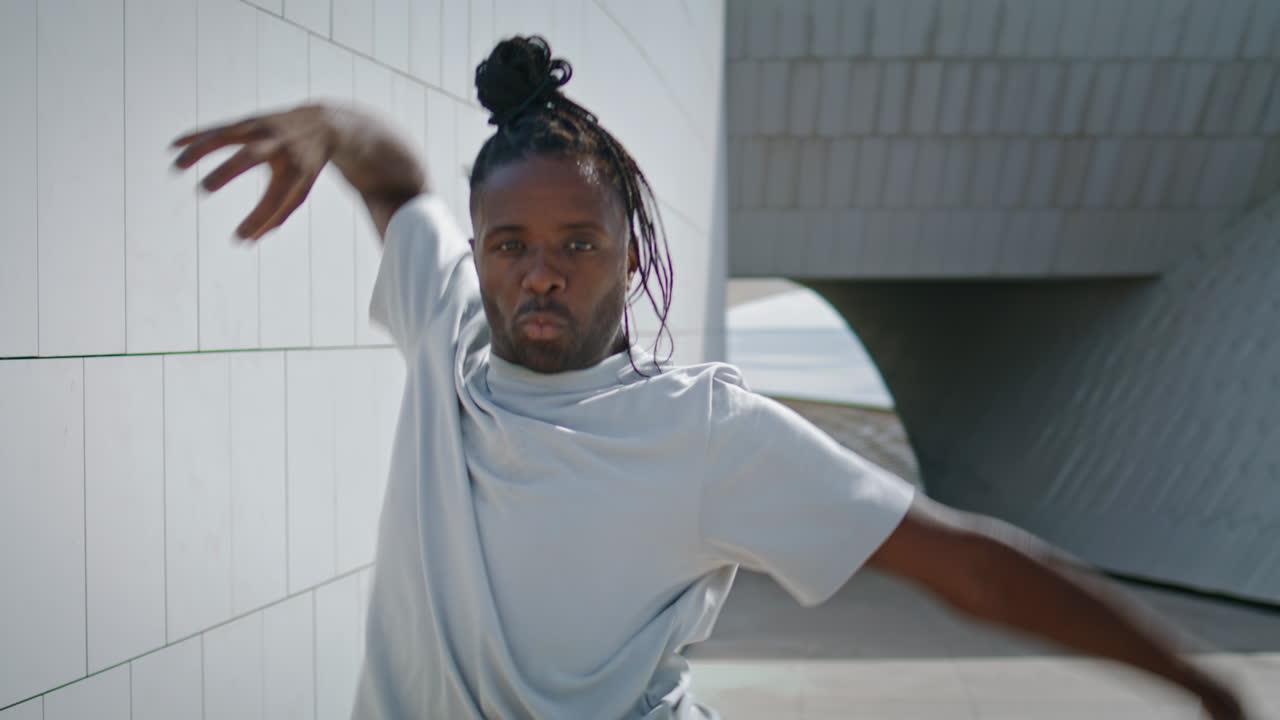 Ragazzo flessibile che balla con le mani, in primo piano. Ballerino con i dreadlocks che si allena nel freestyle.