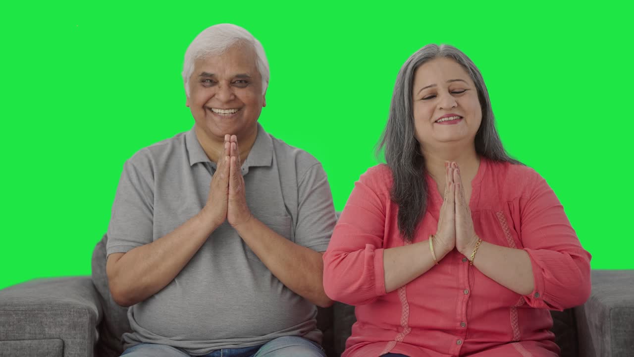 행복한 인도인 은 부부가 '나마스테'를 하는 녹색 스크린