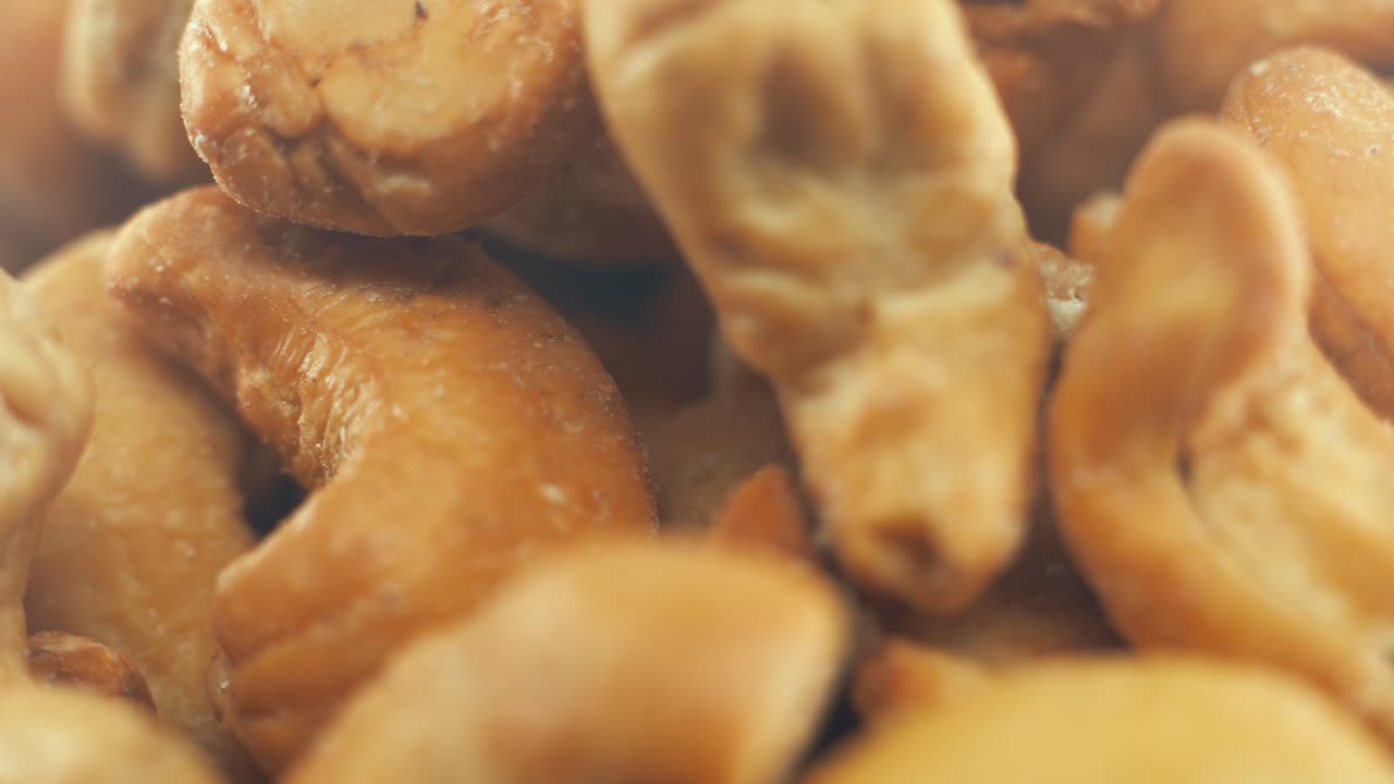 Ripresa macro ravvicinata di una ciotola di anacardi salati tostati su un piedistallo rotante, slow motion, 4k.