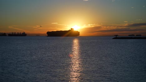 silhouette of a cargo container ship in the harbor amidst a global supply chain crisis at sunset