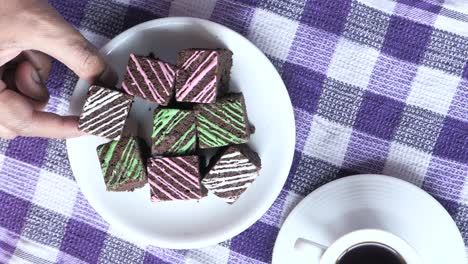 hand picking a brownie from a plate of decorated brownies