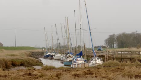 yachts moored on steeping river at gibraltar point, with the tide out showing mud banks. extra wide shot