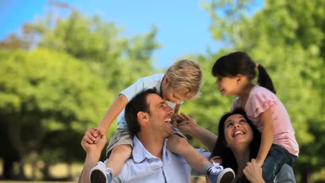 Niños-Sobre-Los-Hombros-De-Los-Padres-Disfrutando-Del-Tiempo-Juntos