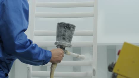 a worker paints a stainless steel metal structure with an airbrush spray gun. dry painting method.