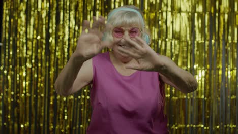 friendly senior old woman waving hands looking at camera with toothy smile, saying hi, greeting