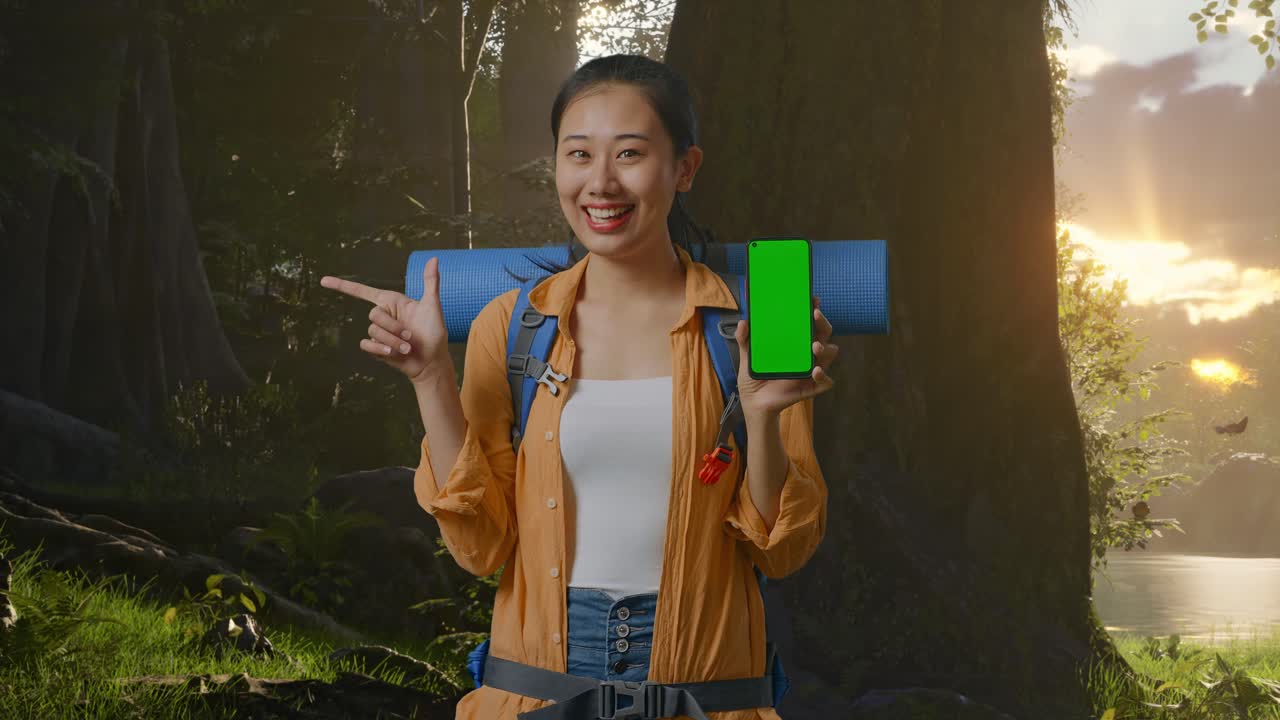 mujer con mochila mostrando teléfono de pantalla verde en un bosque