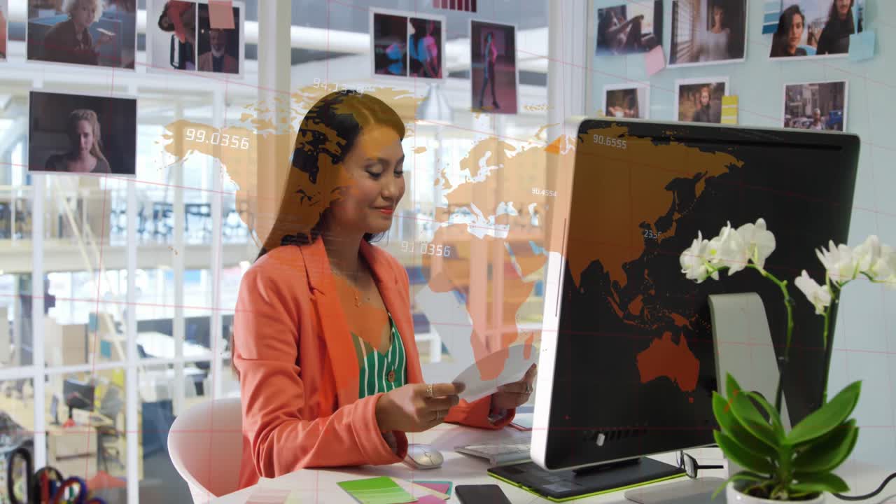 animación de números sobre el mapa del mundo contra la diseñadora gráfica caucásica sosteniendo una muestra de color.