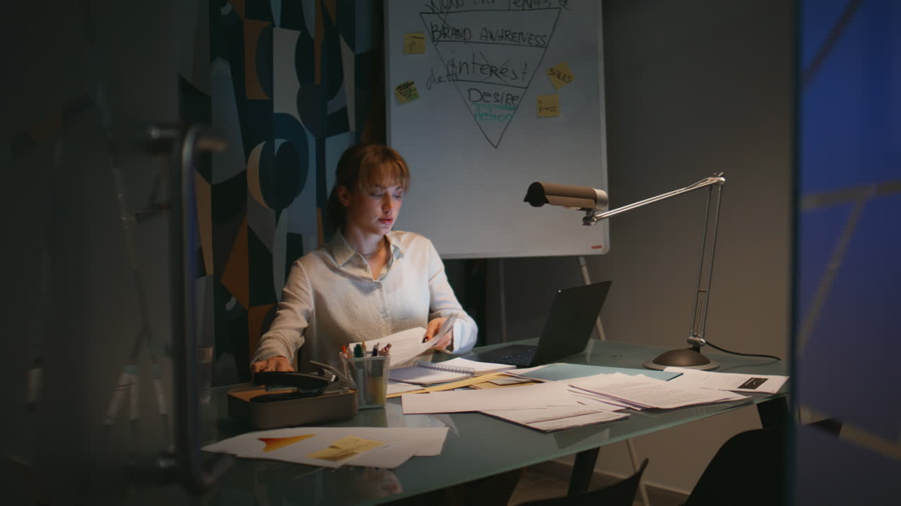 Overworked secretary checking papers working night office. Woman doing paperwork