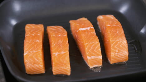 frying four 4 pan fried salmon filets in a black non stick cooking pan