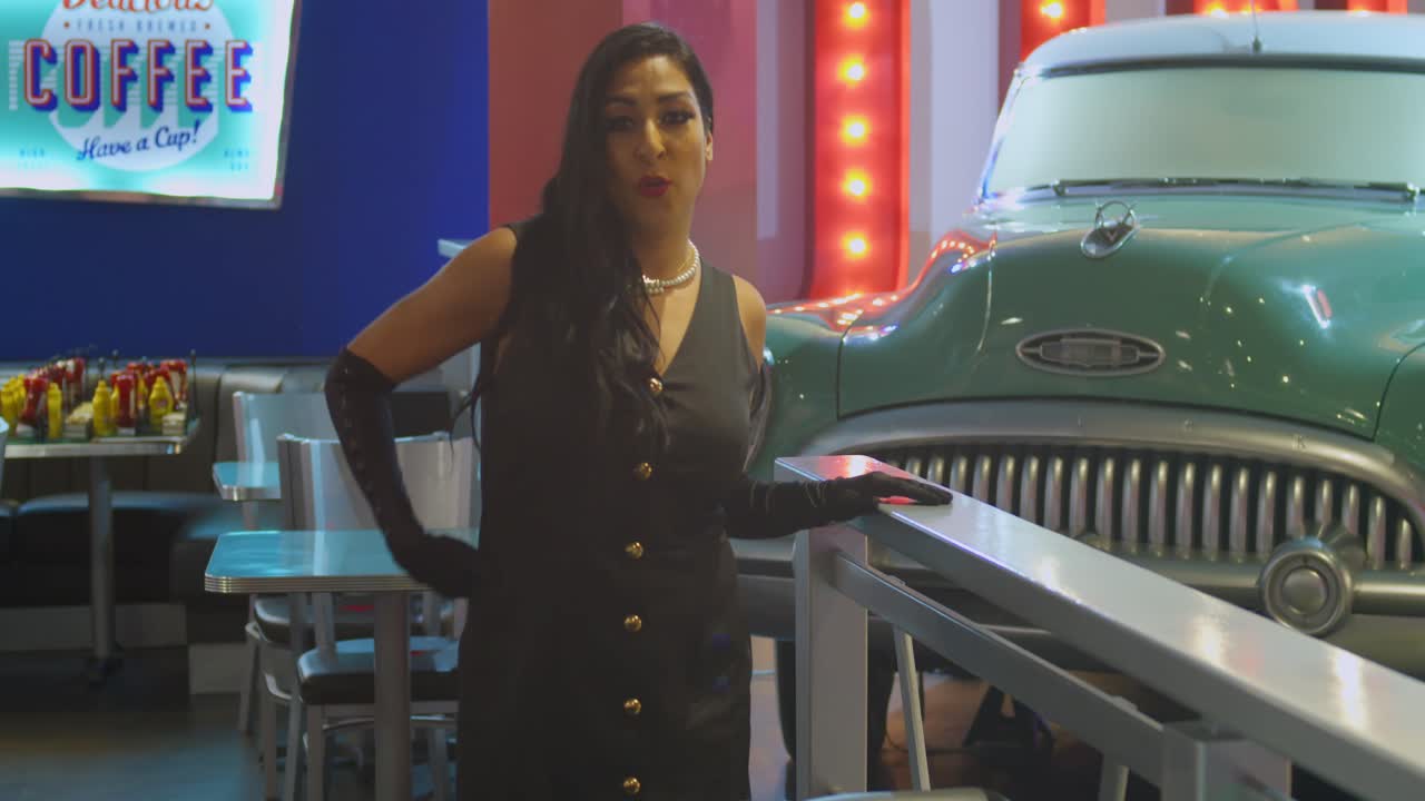 Una giovane donna che balla e canta lungo una colorata strada costiera
