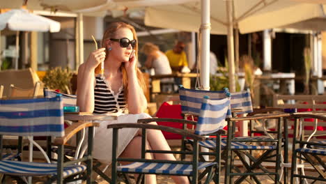 Frau-Spricht-Auf-Ihrem-Handy,-Trinkt-Cocktails-Und-Lächelt