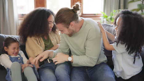 tickle, parents and children laughing on sofa