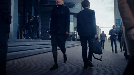 businessman in a suit walking on the street. other office people commute to work or home. it's early morning or late in the evening. footage from the rear. urban city lights in the background.