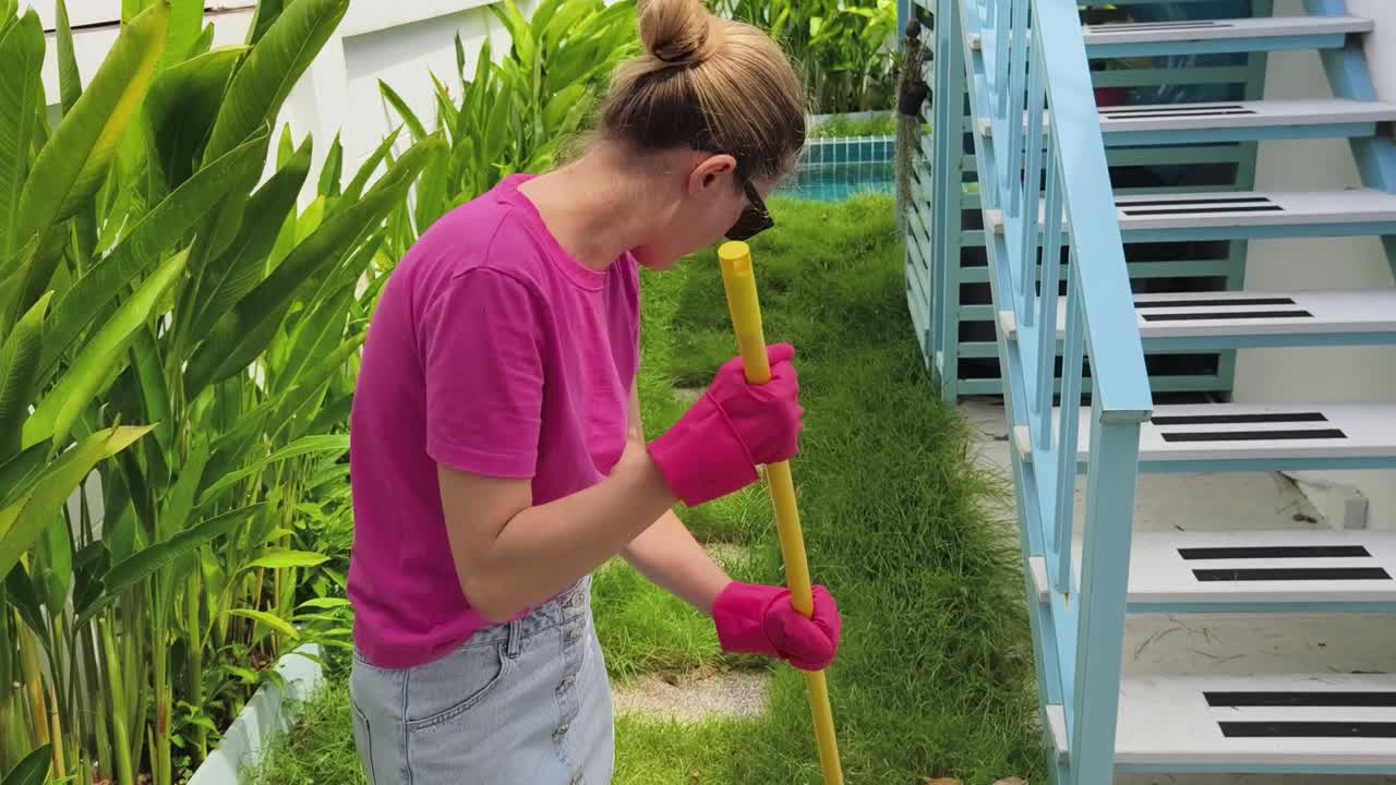 mujer rastrillando el césped en un jardín
