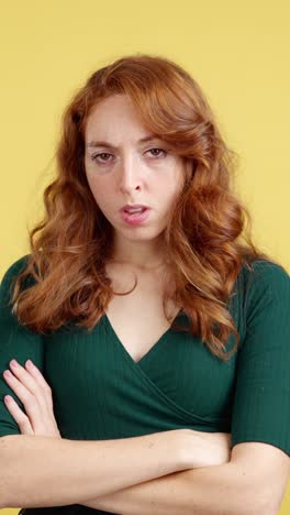 unhappy woman with red hair and crossed arms on yellow background