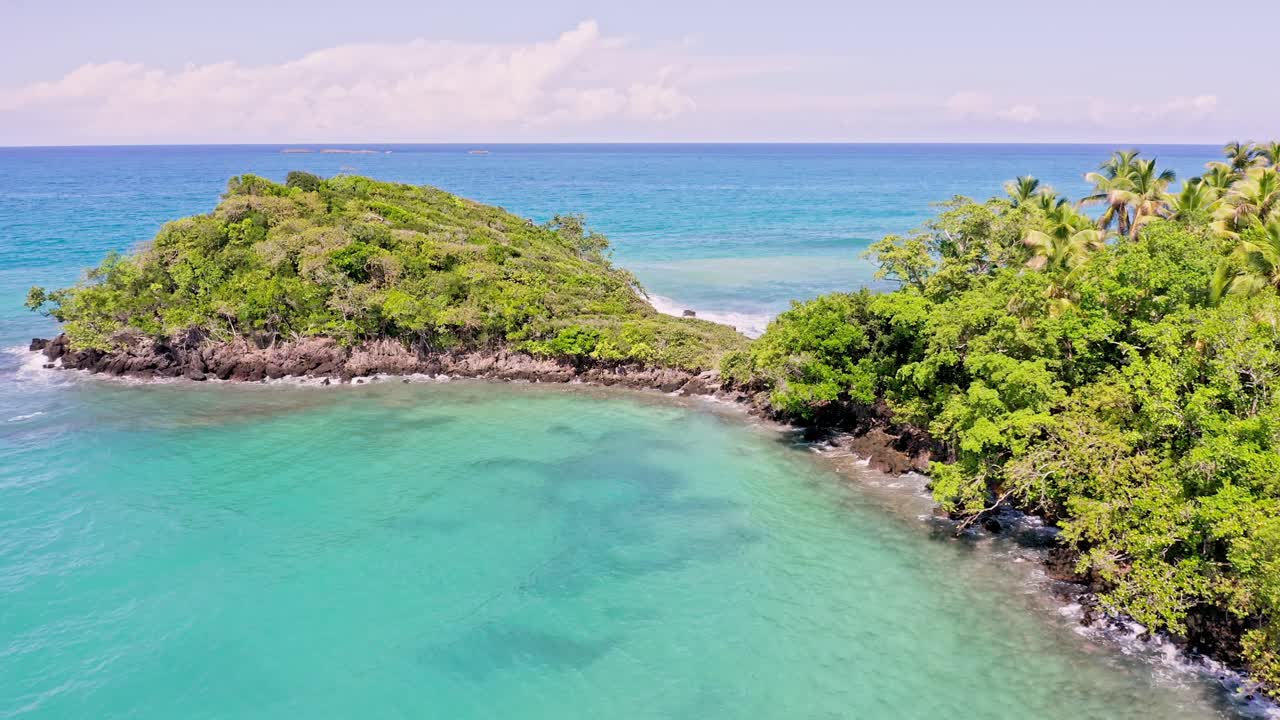 vuelo aéreo lento que muestra una isla tropical con árboles y agua clara del mar caribe durante el día soleado - playa bonita,las terrenas