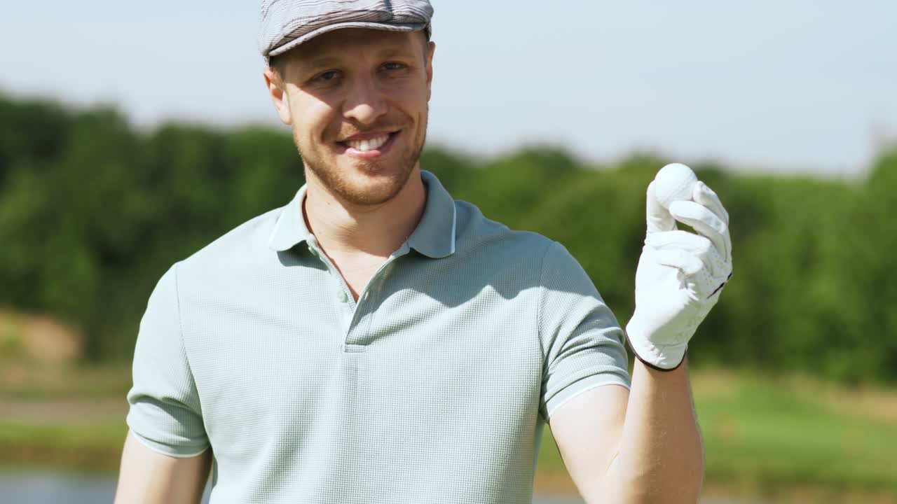 hombre sosteniendo una pelota de golf en un campo de golf