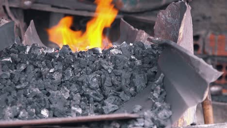 close shot of blacksmith stoking the fires of the forge