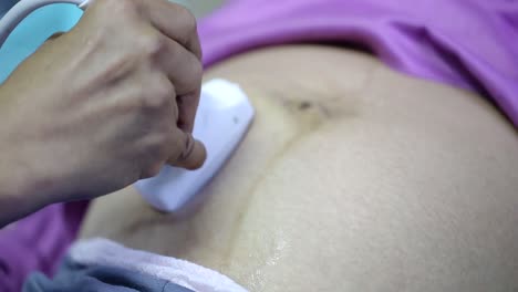 gynecologist checking female patient's fetal life signs with ultrasound scanner