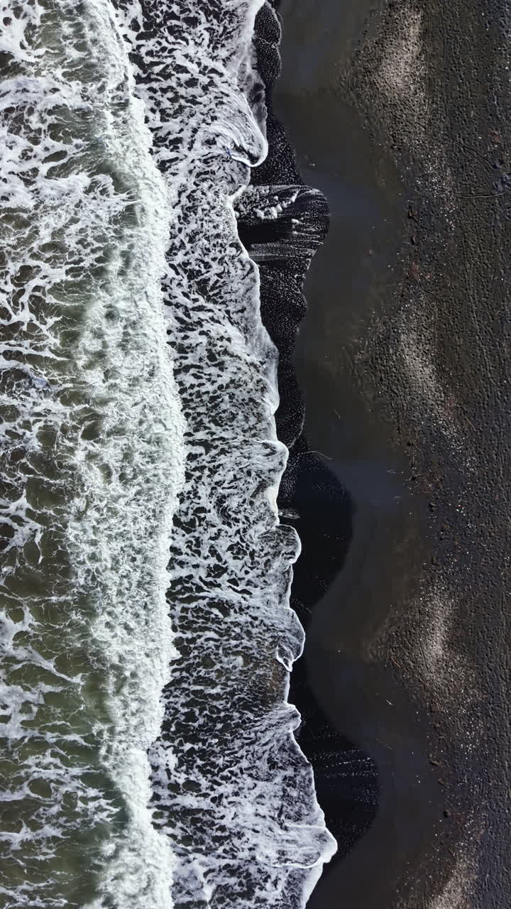 Le onde si infrangono su una spiaggia rocciosa con la bassa marea, mostrando un mix di sabbia e acqua in un ambiente costiero durante il giorno.