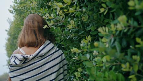 Girl-going-green-leaves-street-on-summer-trip.-Romantic-tourist-pose-touch-bush