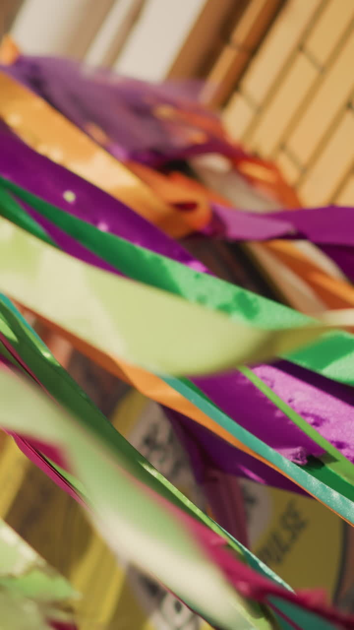 Cintas de color morado y verde energéticas ondeando, artista de desfile lanzando serpentinas por el escenario del festival, bandas de satén brillante, motas de confeti, balanceo dinámico, telón de fondo de neón, ambiente animado para la fiesta