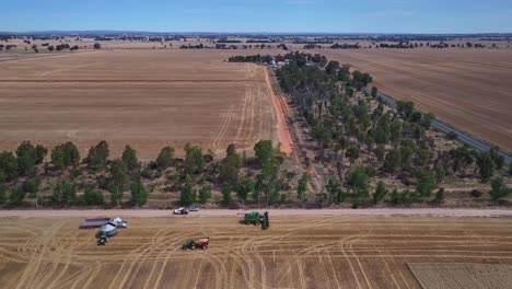 pullback and descent over a wheat paddock with harvesting equipment beyond