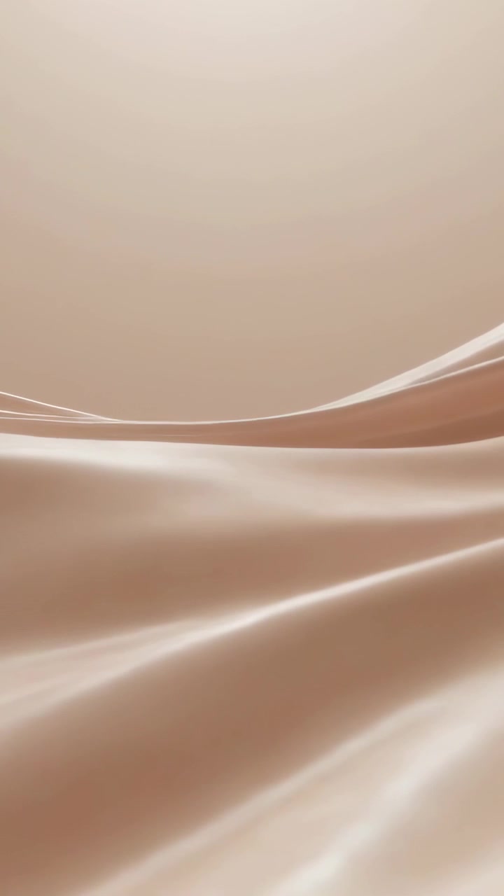 Video verticale: Tessuto di seta che scivola con pieghe che si muovono e riflessi di luce dall'alto su uno sfondo sfumato beige.