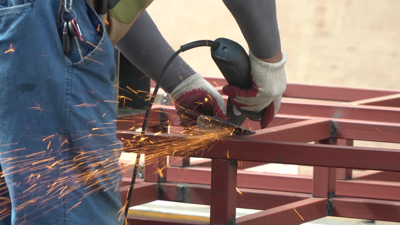 Man worker using angle grinder while working in industrial workshop