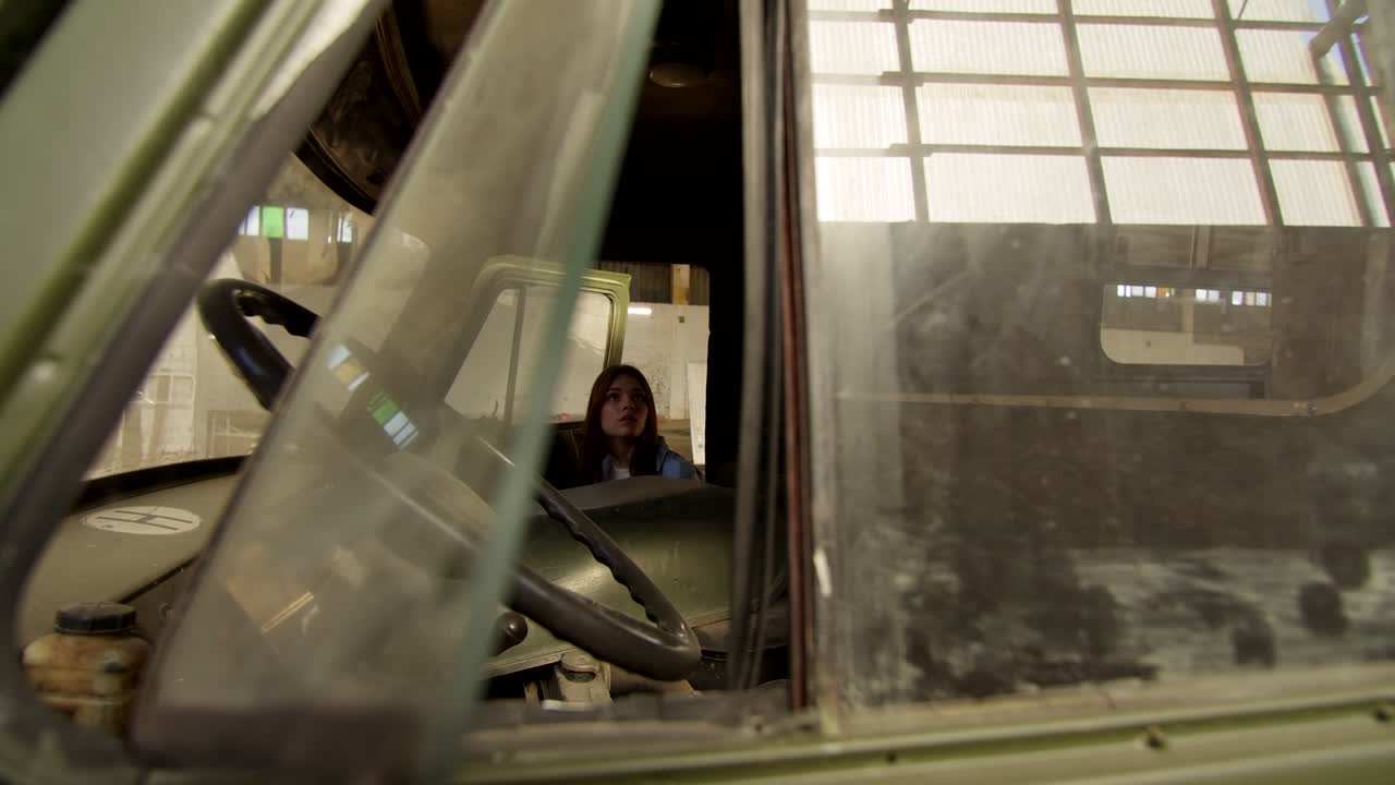 Woman Driving an Old Military Truck in an Abandoned Warehouse