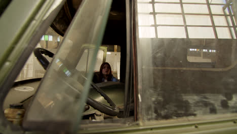 woman driving an old military truck in an abandoned warehouse