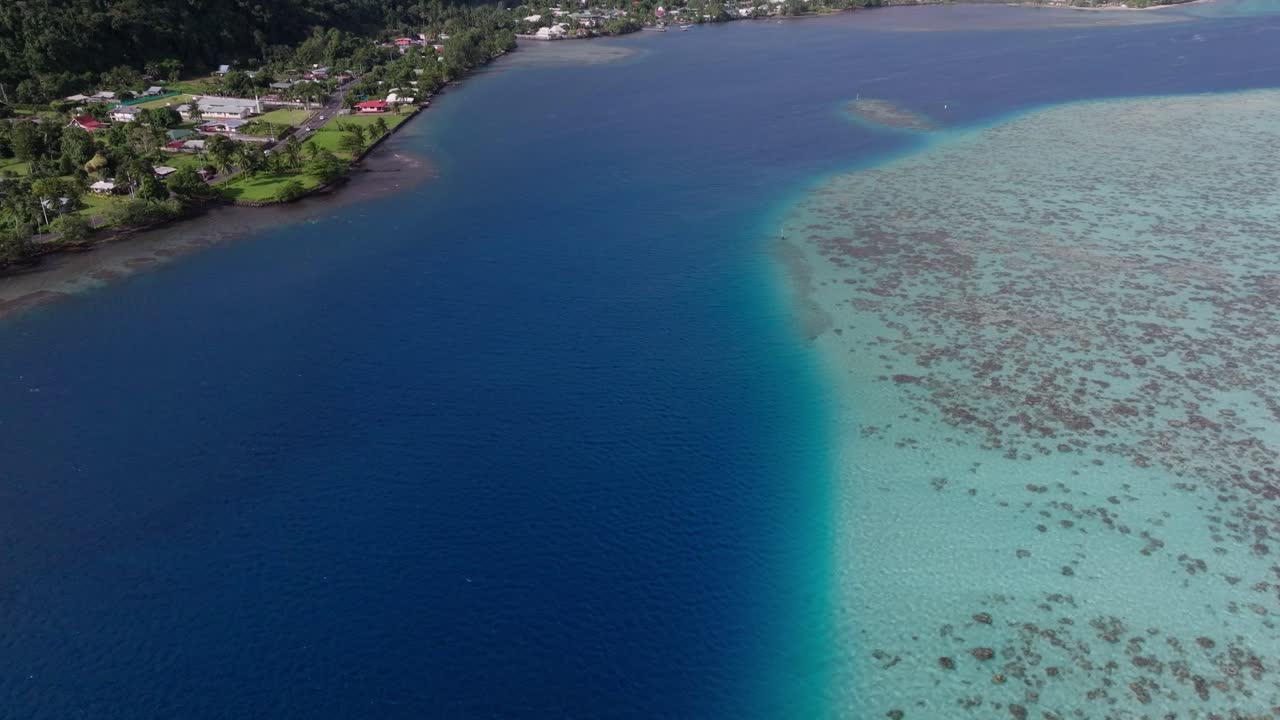Drone video panning up revealing the coastline of Tahiti, French Polynesia. It starts from the coral reefs slowing showing off the mountains