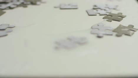 wet grey puzzle pieces laying on a grey surface , covered with water