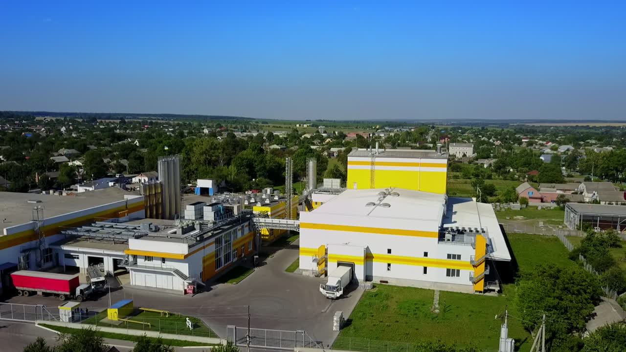 A truck moving out from the factory premises. Private houses and lots of greenery surrounding the industrial plant. Top view.