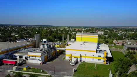 a truck moving out from the factory premises. private houses and lots of greenery surrounding the industrial plant. top view.