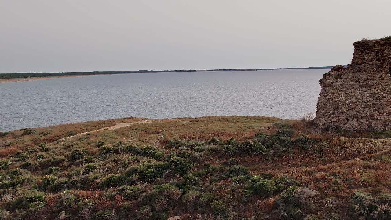 Historisk stentårn nær vand i Sardinien i dagslys